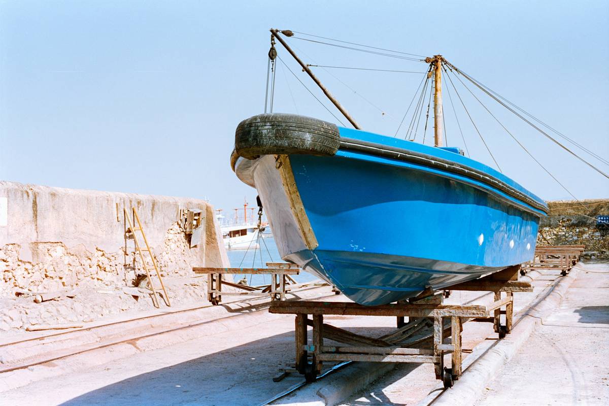 A bright blue boat rests on a wooden trailer